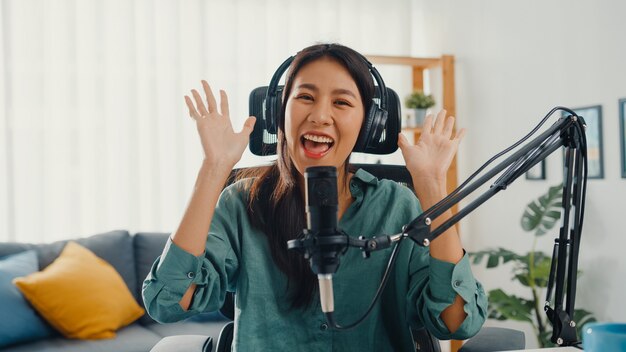 Happy asian girl recording a podcast with headphones and microphone