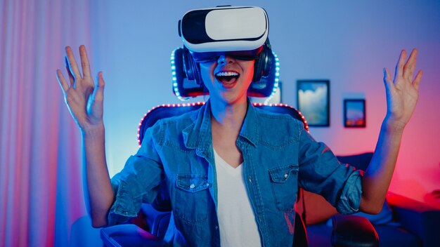 Happy asian girl wearing virtual reality glasses goggles headset with surprise expression