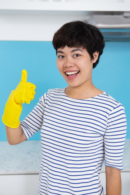 Free photo happy asian housewife showing thumb up in kitchen