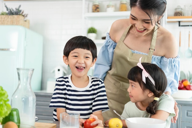 キッチンで息子と娘と一緒に幸せなアジアの母家族の活動を一緒に楽しむ