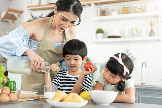 Happy Asian single mother with son and daughter in kitchen Enjoy family activity together