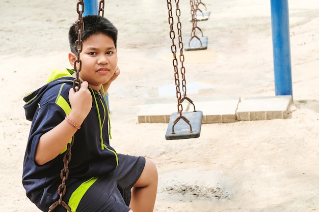 Happy asian sport boy play on swing playground in Garden.