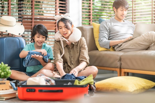 Happy asian sweet family prepare travel exited asian family prepare packing cloth with suitcase luggage travel stuffs for family holiday vacation together at living room at homehappy travel together