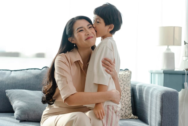 행복한 아시아의 부드러운 아들은 집에서 휴가를 보내는 동안 어머니의 날에 어머니에게 키스한다