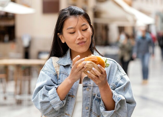 屋外でハンバーガーを食べる幸せなアジアの女性