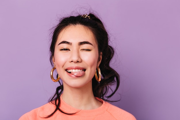 Happy asian woman making funny faces. Front view of trendy japanese young woman in earrings.