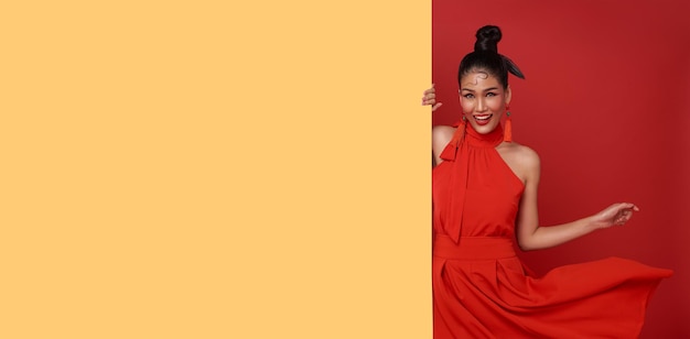 赤い背景の空白のアナウンスバナーと赤いカジュアルな服装で幸せなアジアの女性