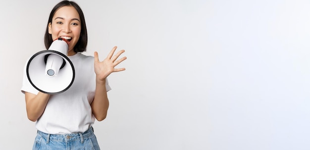 오순절 위에 서 있는 무언가를 광고하는 확성기에서 소리치는 행복한 아시아 여성