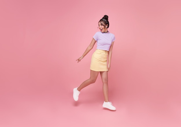 Happy Asian woman smiling and  Jumping like running while her looking back at pink copy space background