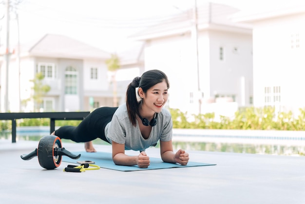 Donna asiatica felice che allunga esercizio e allenamento yoga al mattino a casa