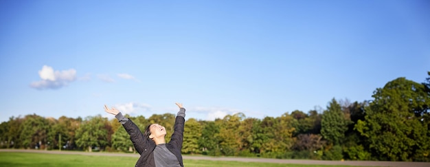 Free Photo happy asian woman stretching her hands sitting on bench with excited face smiling pleased feeling