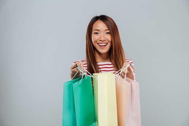 Happy asian woman in sweater holding packages