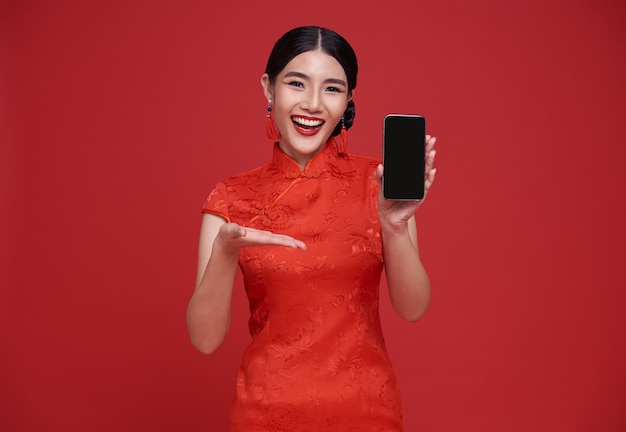 Happy asian woman wearing traditional cheongsam qipao dress showing mobile phone