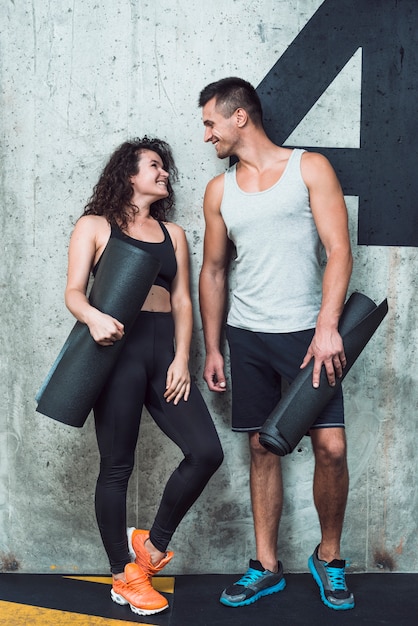 Happy athletic couple with exercise mat looking at each other