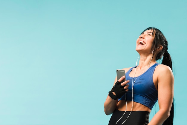 Бесплатное фото Счастливая атлетическая женщина наслаждаясь музыкой в наушниках