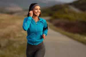 Free photo happy athletic woman listening music on earphones while running in nature in the morning copy space