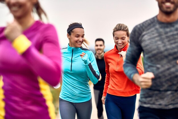 Happy athletic women having fun while jogging with group of people in nature