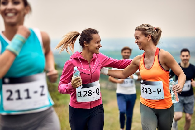Счастливые спортсменки поддерживают друг друга во время марафона на природе