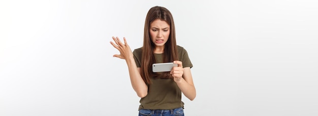 Happy attractive brunette girl joying win in video game on smartphone isolated over grey background