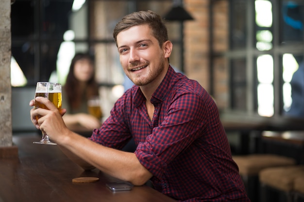 Happy Attractive Man Holding Glass of Beer in Pub