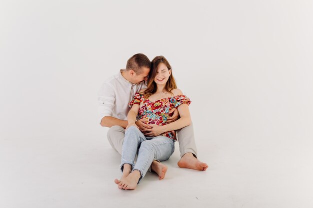 Happy and attractive pregnant couple posing in studio