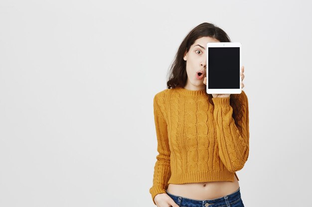 Happy attractive young girl showing digital tablet screen