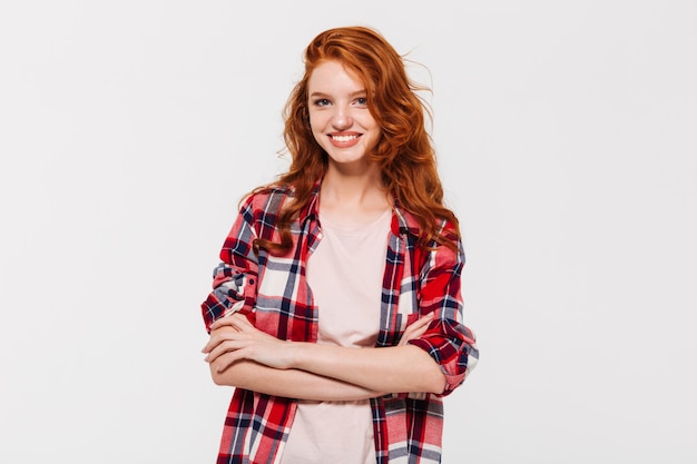 Happy attractive young redhead lady with arms crossed.