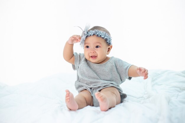 Happy baby sitting on a white bed