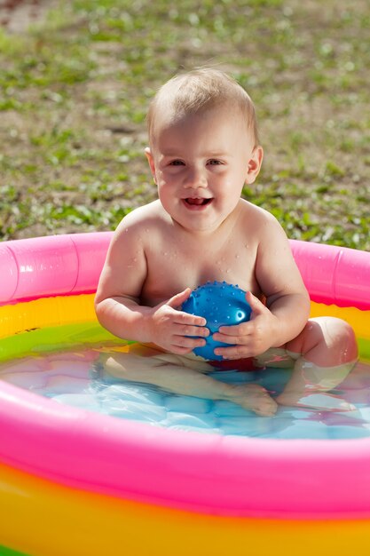 Счастливый ребенок плавает в надувном бассейне