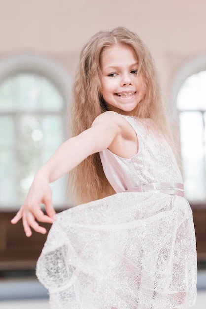 Happy ballerina girl with long hair holding her dress