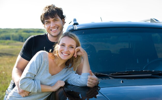 Happy bautiful young couple standing near the car