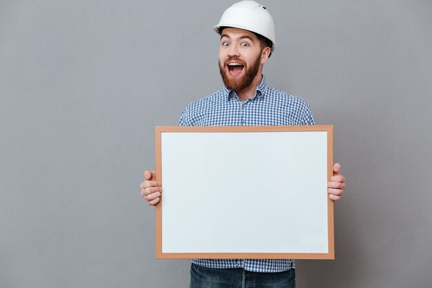 Happy bearded builder holding blank board