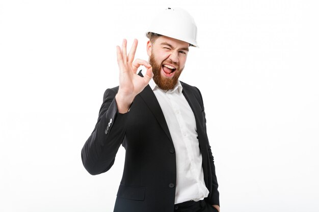Счастливый бородатый деловой человек в защитном шлеме, показывая знак ОК