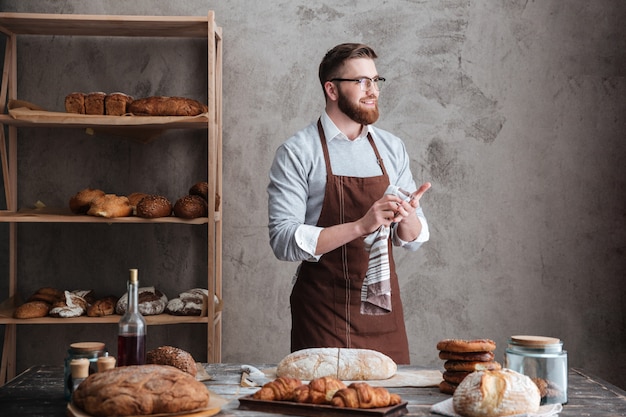 Free photo happy bearded man baker standing near a lot of bread.