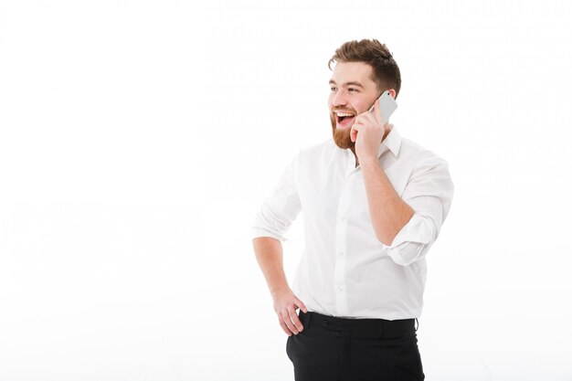 Happy bearded man in business clothes talking by smartphone