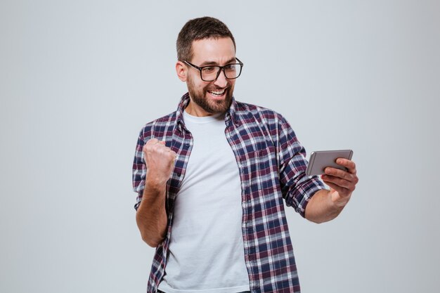 Happy Bearded man in eyeglases looking at phone