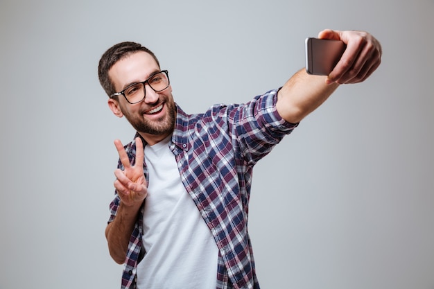 Uomo barbuto felice in occhiali da vista che fanno selfie