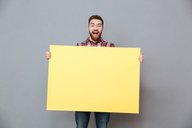 Happy bearded man holding blank board