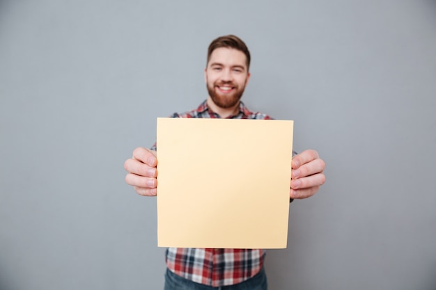 Счастливый бородатый мужчина держит чистый лист бумаги