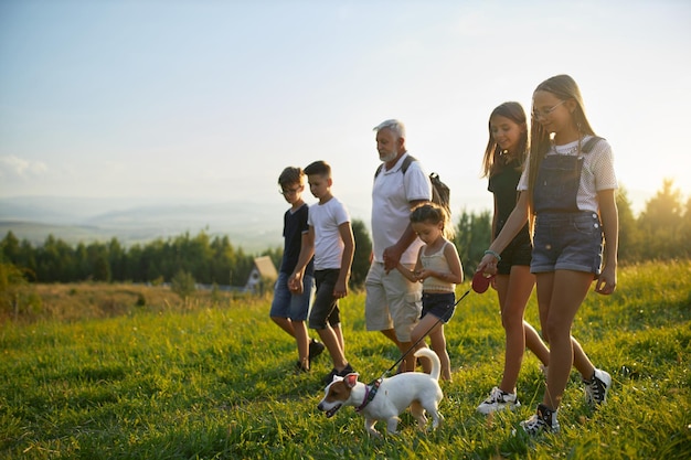 Un uomo barbuto felice con i bambini che cammina lungo una collina in estate