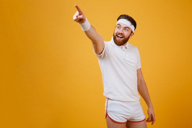 Happy bearded sportsman pointing away