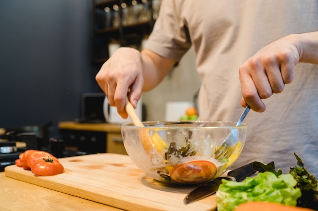 Happy beautiful asian man prepare salad food in the kitchen