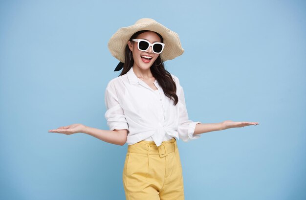 Счастливая красивая азиатка, одетая в летнюю одежду, улыбается приветственным жестом открытой руки