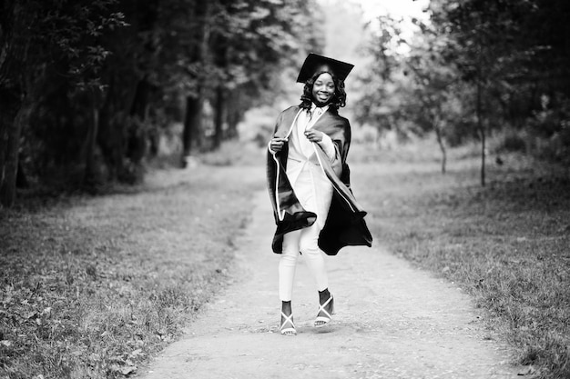 帽子とガウンの卒業生と幸せな美しい黒人アフリカ系アメリカ人の女の子