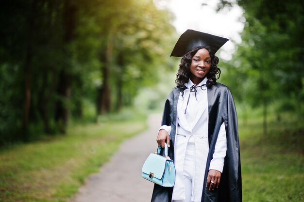 Happy beautiful black african american girl with hat and gown graduates