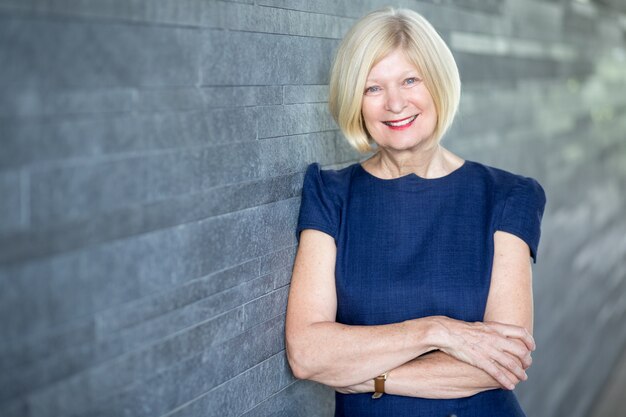 Happy beautiful female executive leaning on wall