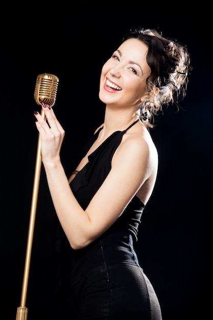 Free photo happy beautiful girl singer laughing behind retro microphone