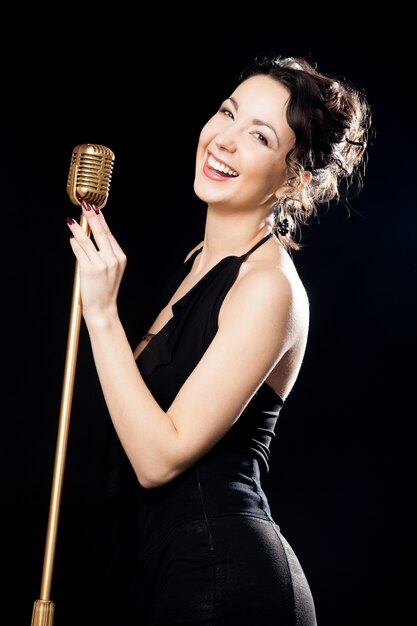 Happy beautiful girl singer laughing behind retro microphone