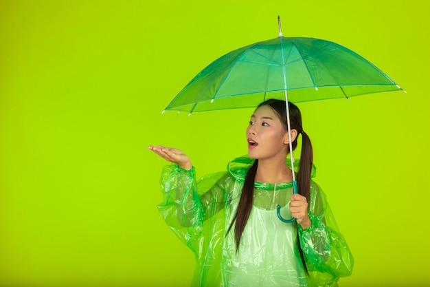 Happy beautiful girl, wearing green clothes, umbrella and coat. rainy day.