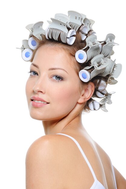 Happy beautiful girl with curlers on her head on white